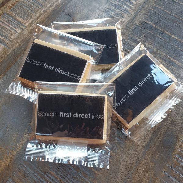 A group of biscuits from The Biskery of rectangular shapes, wrapped in compostable bags, on a wooden table