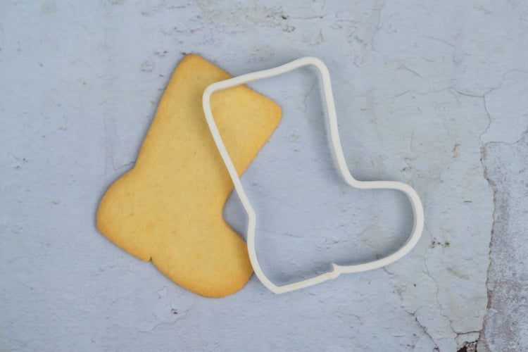 Cookie cutter in the shape of a boot. Next to the boot shaped biscuits that was made using the bespoke 3d printed cookie cutter.