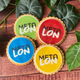 4 colourful META branded biscuits on a wooden backdrop with green leaves