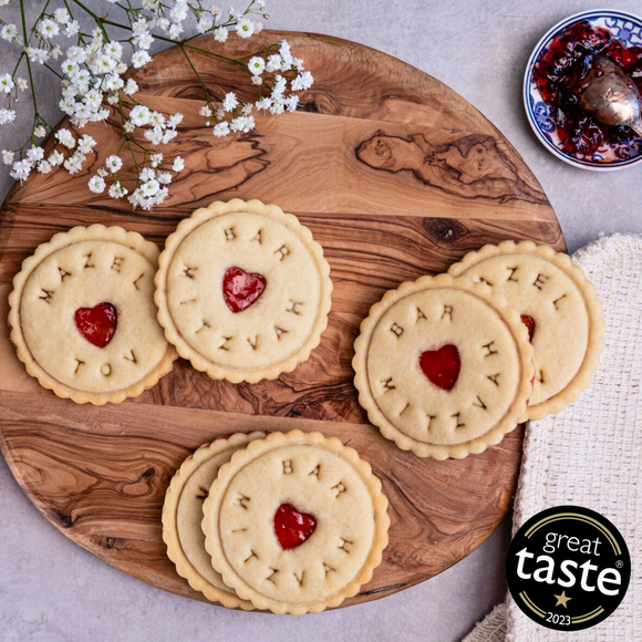 Delicious biscuits with jam filling, arranged on a rustic wooden cutting board.