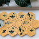 A set of yellow hexagonal beeswax-style fondant biscuits with black printed bee designs and two reading 'Bee Kind,' arranged in a letterbox-friendly pack with decorative green leaves around them.
