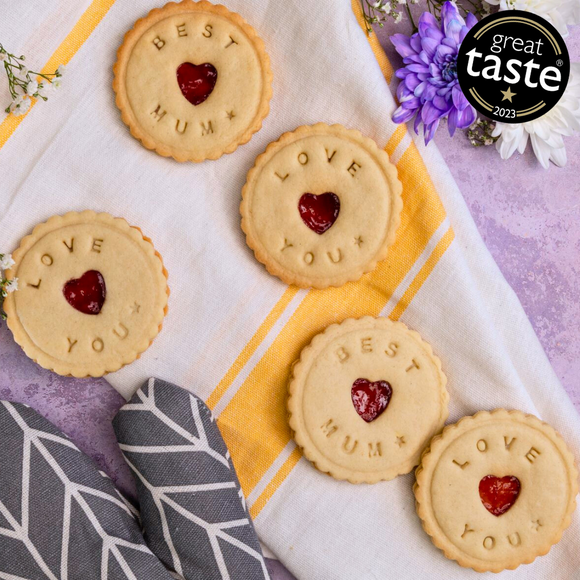 A close-up photo of handmade biscuits that spell out "BEST MUM," "LOVE YOU," and "GREAT TASTE 2023" on a white towel