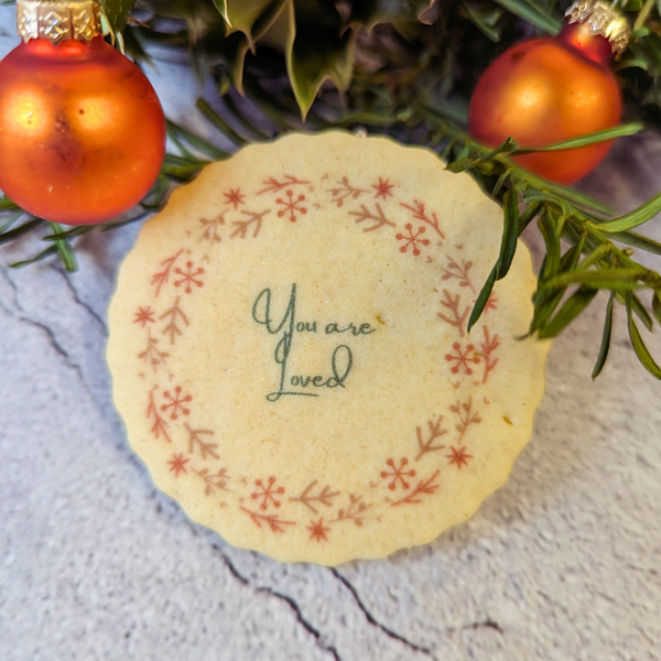 A photo of a biscuit with the words "You are loved" and a wreath on it