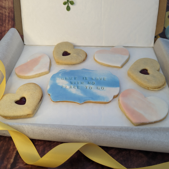 Six heart-shaped jam and marbled fondant icing biscuits. One larger biscuit with the words "GRIFF IS LOVE WITH NO PLACE TO GO" written in icing