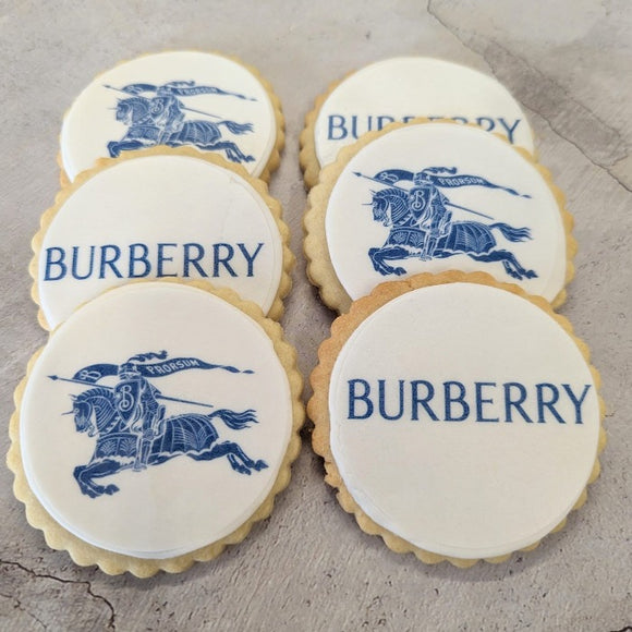 Image of a stack of four cookies with the Burberry logo on them. The cookies are on a white background. The logo is in the center of the cookies and is made up of the words "BURBERRY" in blue letters.