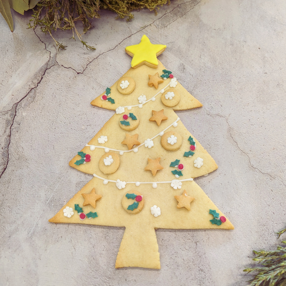 Christmas tree biscuit made of butter dough, decorated with sprinkles and a yellow star.