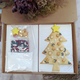 A box from The Biskery containing a Christmas tree made of butter dough, with a bag of sprinkles and icing sugar next to it