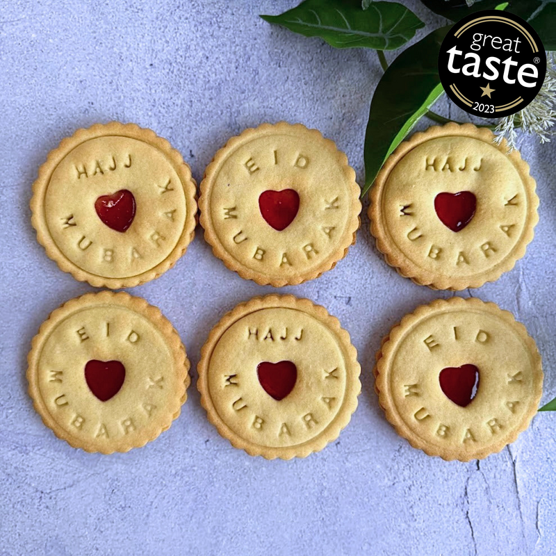 Six cookies with 'Eid Mubarak' text and red hearts on a light blue background, featuring the Great Taste 2023 award.