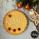 Giant Personalised Christmas Cookie in a gift box, decorated with white icing and the name "Andrew". Festive decorations and a Great Taste award logo are visible in the background.