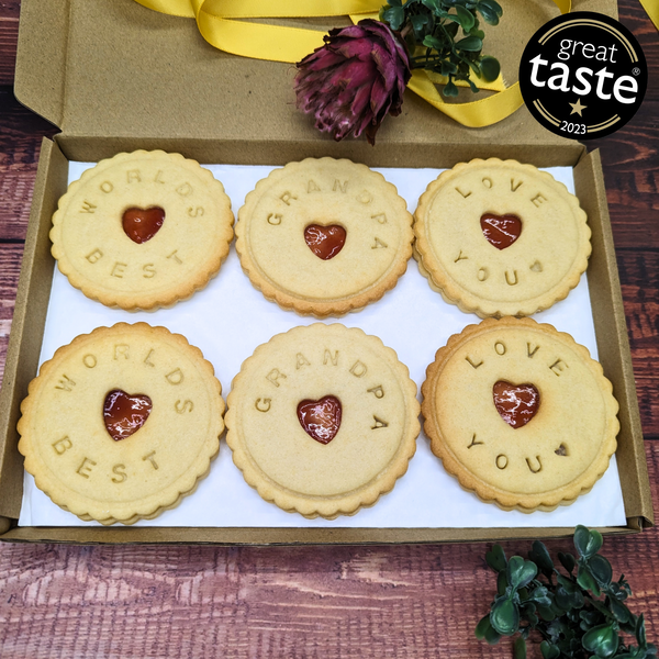 Box of cookies with personalized messages and a 'Great Taste' award on a wooden surface.