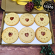 Box of cookies with personalized messages and a 'Great Taste' award on a wooden surface.
