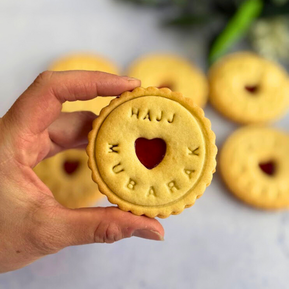 Hand holding Eid & Hajj Mubarak Jam Biscuit – handmade cookies with jam heart, perfect festive gift for Eid or Hajj celebrations.