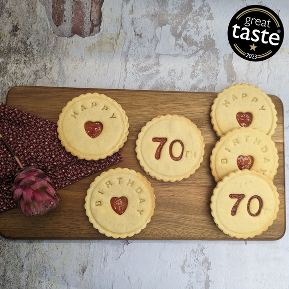 Delightful Happy 70th Birthday biscuits, arranged on a wooden cutting board, with a ribbon
