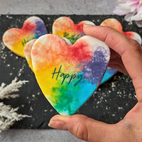 Colourful rainbow biscuits with 'happy' written on them.