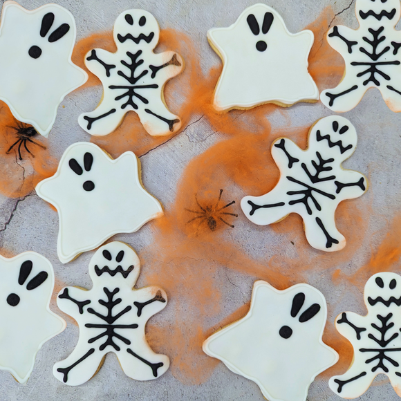 Iced Ghost & Skeleton Party Pack biscuits stuck on the spider's web. The biscuits are shaped like ghosts and Skeletons .