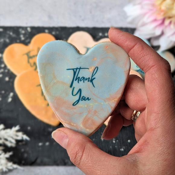 Heart-shaped iced thank you biscuits decorated with a marble-style 'Thank You' message