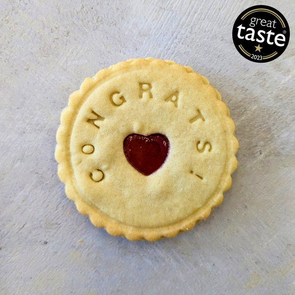 Close-up of a biscuit with a heart-shaped cut-out and 'Congrats' written on it