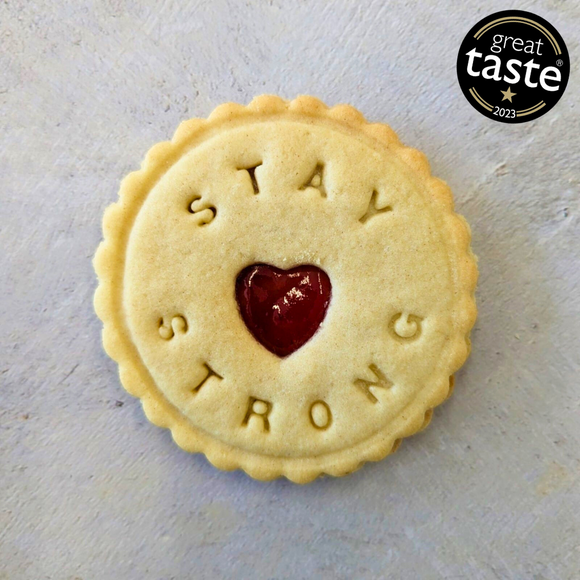 Close-up of a biscuit with a heart-shaped cutout and 'Stay strong' written on it