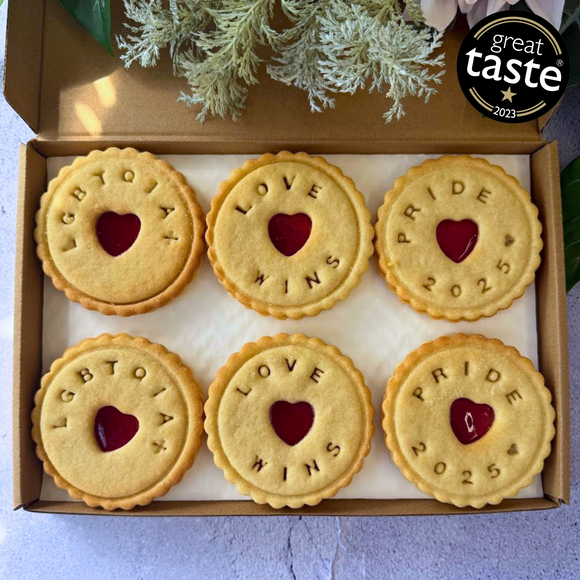 A box of six jam biscuits with the words "LGBTQIA+", "LOVE WINS", and "PRIDE 2025" impressed on them, celebrating Pride with a delicious treat.