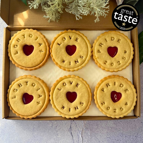 A box of six jam biscuits with the words "LGBTQIA+", "LOVE WINS", and "PRIDE 2025" impressed on them, celebrating Pride with a delicious treat.