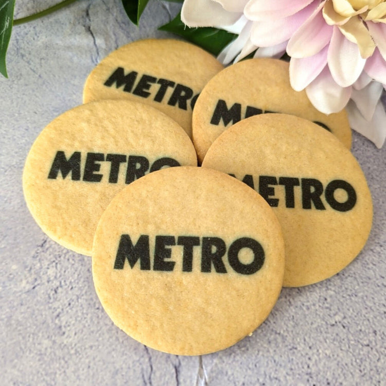 Round cookies with 'METRO' branding on a light surface with flowers in the background