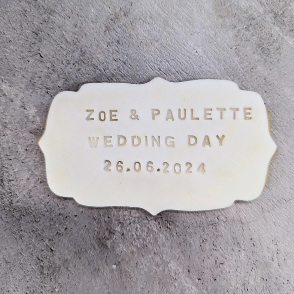 A plaque biscuit with the names "Zoe" and "Paulette" and the wedding date "26.06.2024" engraved on it. A beautiful keepsake to commemorate their special day