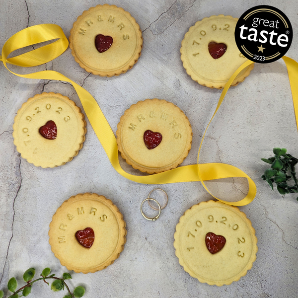 Stack of Jam wedding biscuits with heart-shaped biscuits at the centre, arranged on a table, adorned with a yellow ribbon for the MR&MRS couple. 