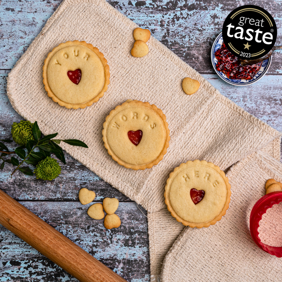 Three heart-shaped jam biscuits on a table, ready for dunking.