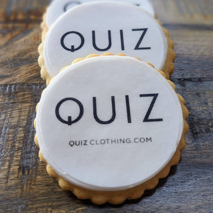 Quiz clothing branded logo printed biscuits. on a wooden table 