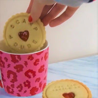 Dunking jam biscuit in cup of tea