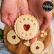 A signature Thank You jam biscuit placed in hands. With more of the same biscuits appearing out of focus in the background.