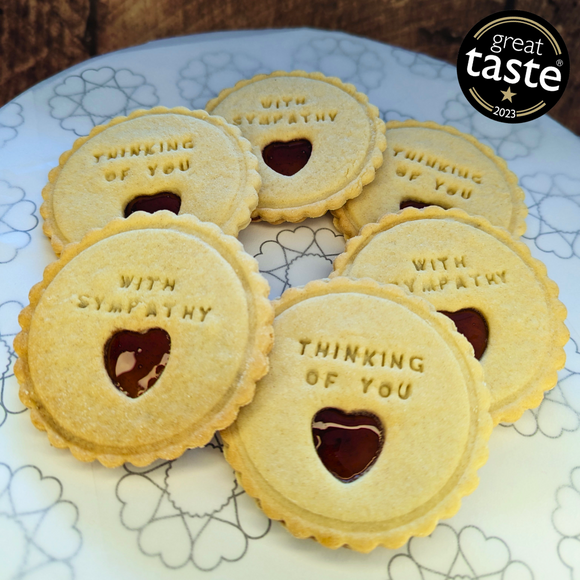 Plate of jam biscuits from The Biskery company, adorned with words 'THINKING OF YOU' and 'WITH SYMPATHY', featuring heart-shaped cut-outs