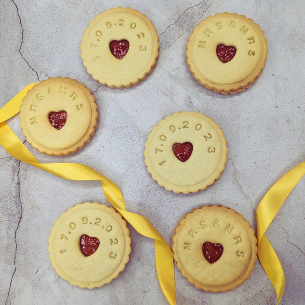 Stack of Jam wedding biscuits with heart-shaped biscuits at the centre, arranged on a table, adorned with a yellow ribbon for the MRS&MRS couple. 