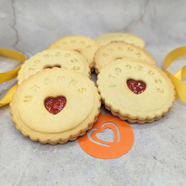  Stack of Jam biscuits with a heart-shaped one in the middle, arranged on a table. The heart-shaped biscuit is adorned with a stencil of a love heart, a popular British biscuit.