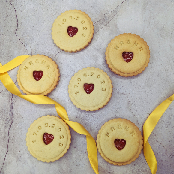 Stack of Jam wedding biscuits with heart-shaped biscuits at the centre, arranged on a table, adorned with a yellow ribbon for the MR&MR couple. 