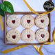 A box of six bespoke jam biscuits with heart-shaped cut-outs in the middle. The biscuits are decorated with the words 'Congratulations on your wedding!'