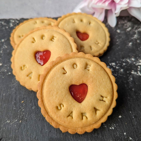 Close-up of Custom Wedding Names Biscuits with heart-shaped holes, stacked on a stone table 