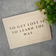 A postcard with 'to get lost is to learn the way' on it.